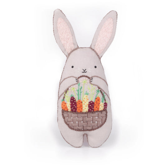 Stuffed bunny toy with a basket of carrots on a white background