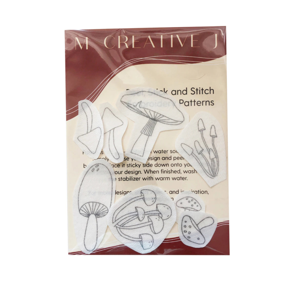 Mushroom-themed craft and stitch patterns in a clear plastic bag with a cream and dark red label. The patterns are shown as white die-cut shapes with black outline drawings of various mushrooms.