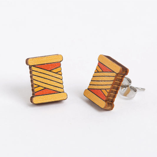 Wooden spool earrings with orange and yellow pattern on a white background