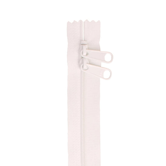 Close-up of a white zipper on a light pink background