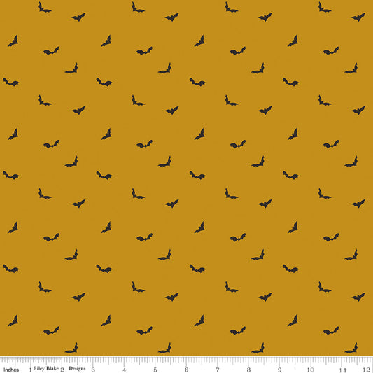 Pattern of small black bats on a mustard yellow background with a fabric ruler at the bottom.