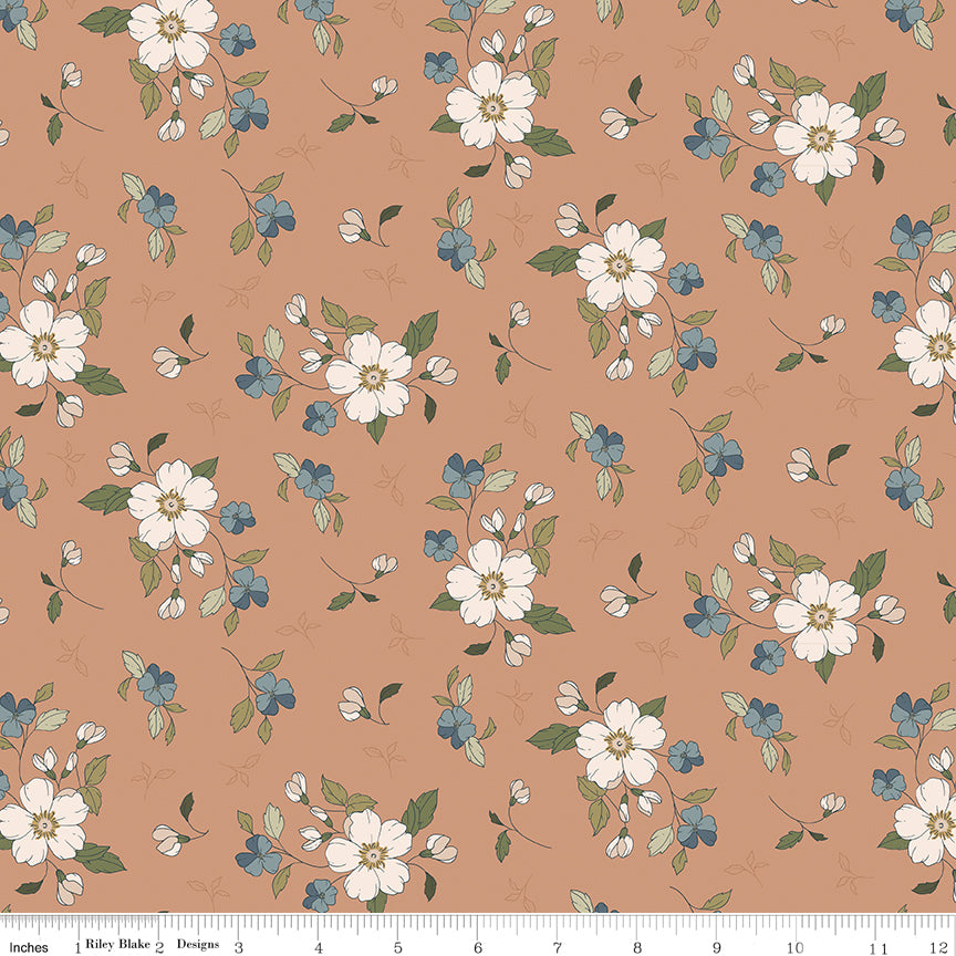 A repeating floral pattern on a warm peach background, featuring large white blossoms, smaller blue flowers, and green leaves. A ruler along the bottom edge shows scale, and the text 'Riley Blake Designs' is visible in the lower left corner.