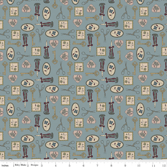 A repeating fabric pattern featuring vintage sewing tools and motifs, including scissors, thread spools, pattern books, and keys, in muted tones of dusty blue, beige, and brown. A ruler at the bottom indicates the scale of the print.