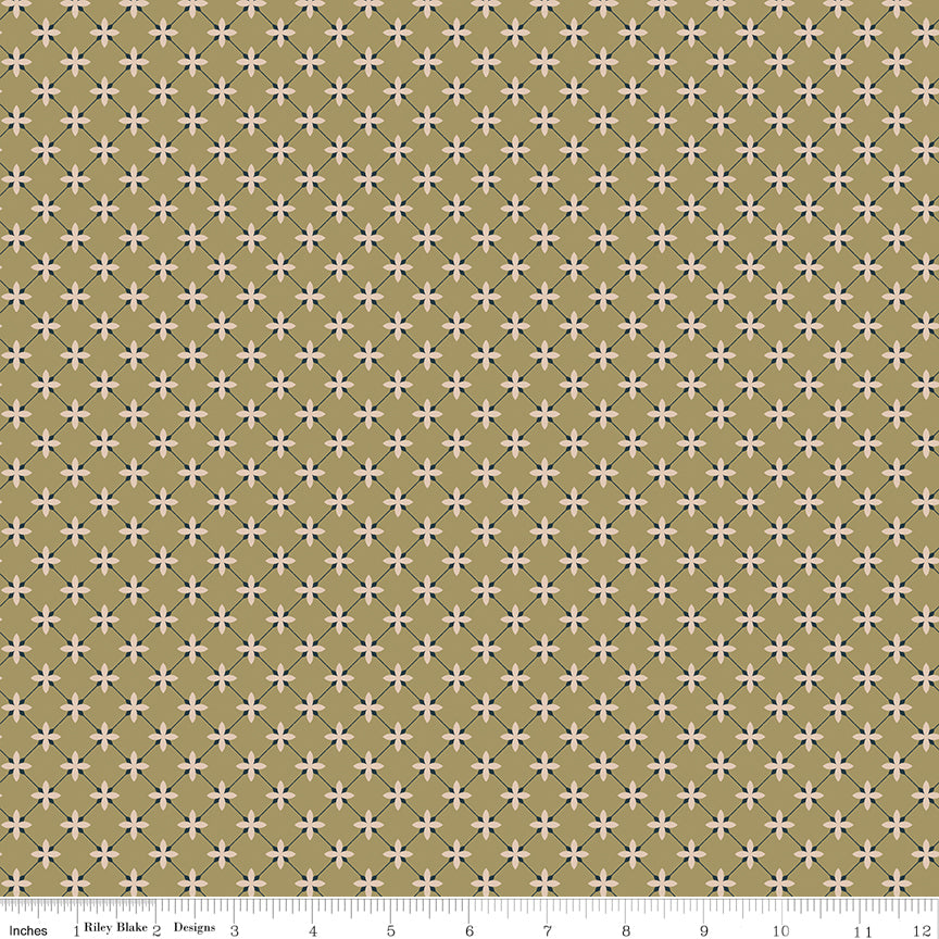 A repeating geometric fabric pattern featuring small white four-petal starbursts on a muted olive-gold background, with a white ruler scale along the bottom edge showing measurements.