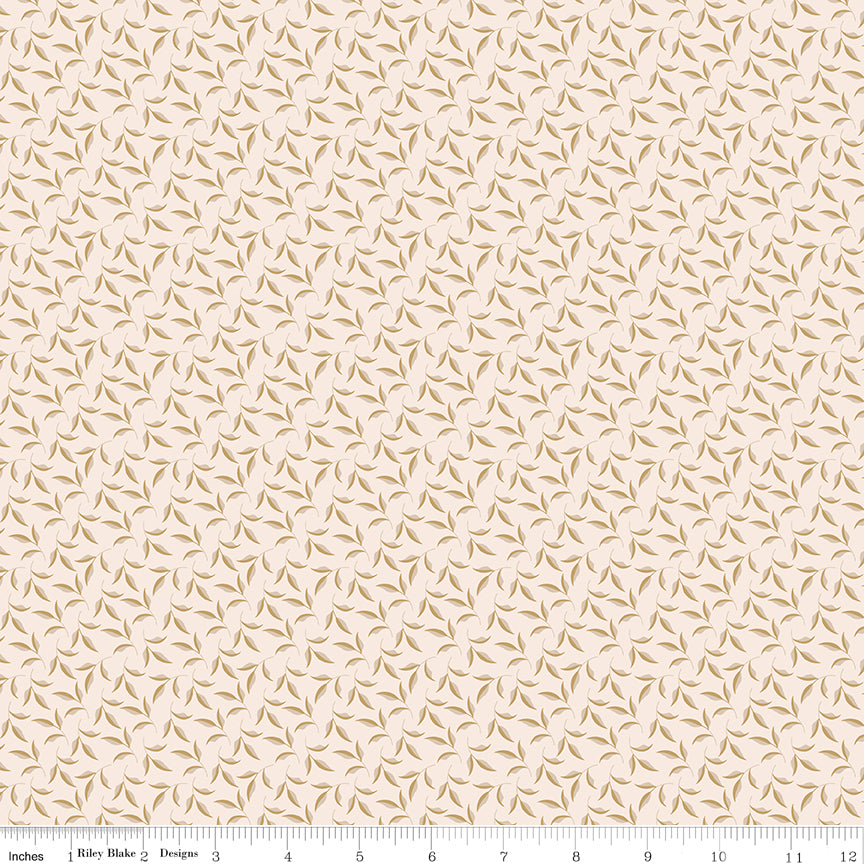 A repeating fabric pattern featuring small brown leaf-like motifs on a warm cream background, with a ruler along the bottom edge showing scale. The brand name 'Riley Blake Designs' is visible on the ruler.