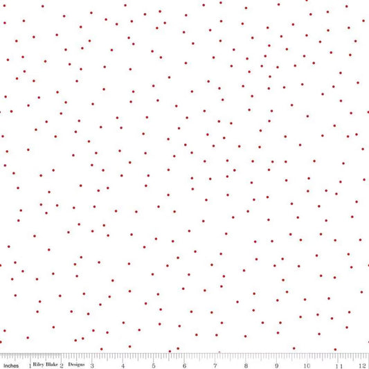 A white fabric or material swatch with a scattered pattern of small dark red dots, shown flat with a ruler along the bottom edge for scale.