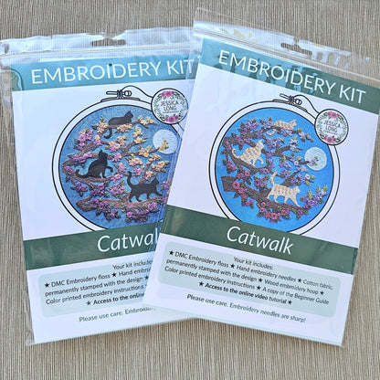 Two embroidery kits labeled 'Catwalk' on a wooden surface