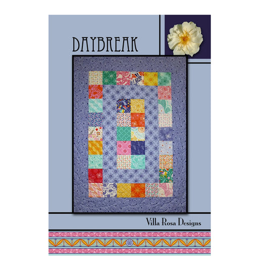 A quilt pattern cover for 'Daybreak' by Villa Rosa Designs, featuring a central patchwork quilt design with a purple floral border and multicolor square patches, set against a light blue and purple background with a decorative flower illustration.
