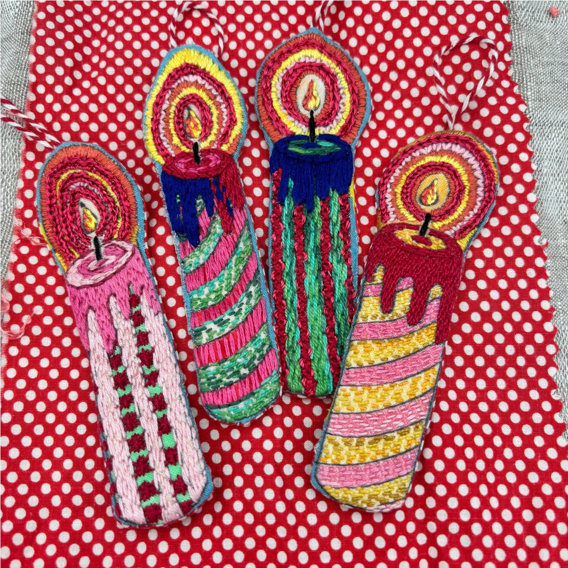A collection of four embroidered candle ornaments