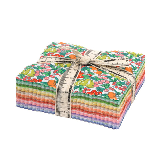 A stack of colorful patterned fabric squares tied with a cream ribbon printed with a measuring tape design, on a plain white background.