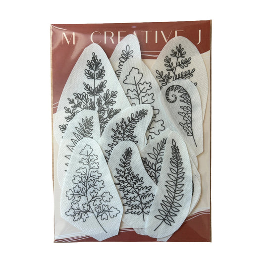 A set of eight white fabric stamping blocks with black botanical leaf line drawings, packaged in a brown cardboard sleeve with the brand name 'M. CREATIVE J' visible at the top.