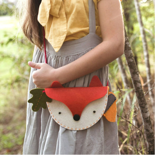 Person wearing a fox-shaped crossbody bag in a forest setting