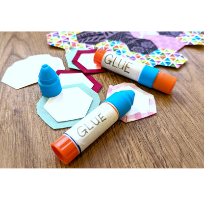 Two glue sticks with colorful shapes on a wooden surface