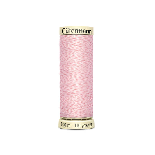 Spool of pink Gutermann thread on a white background