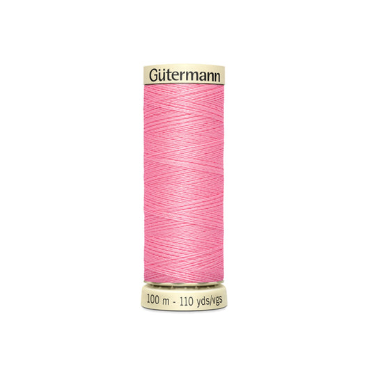 Spool of pink Gutermann thread on a white background