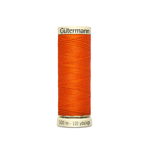 Orange spool of Gutermann thread on a white background