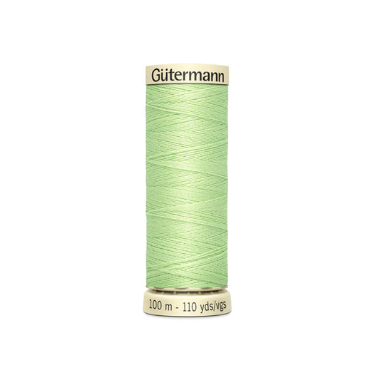Green spool of Gütermann thread on a white background