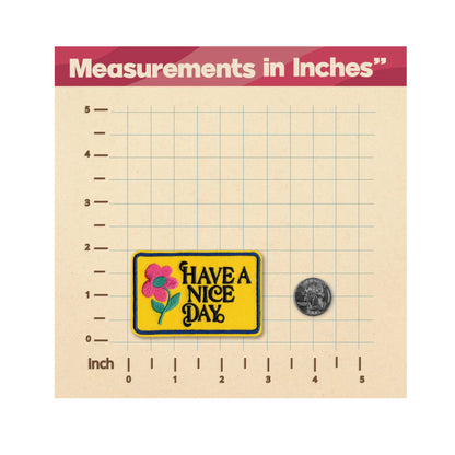 A yellow rectangular patch with the words “HAVE A NICE DAY” and a pink flower design, shown on a beige measurement grid with an inch scale and a coin for size reference. The top banner reads “Measurements in Inches”.