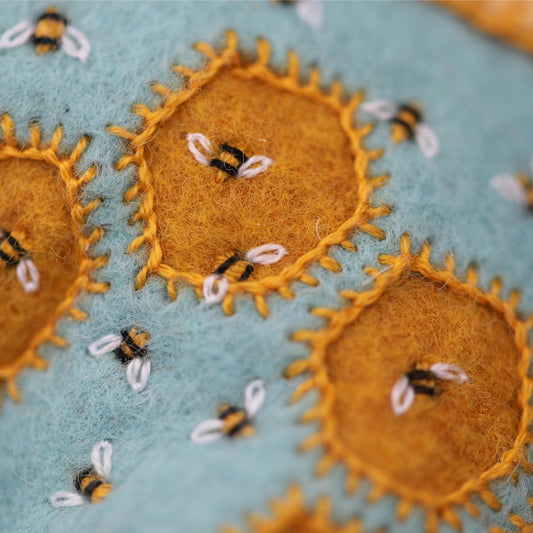 Close-up of embroidered suns with bees on a textured fabric background