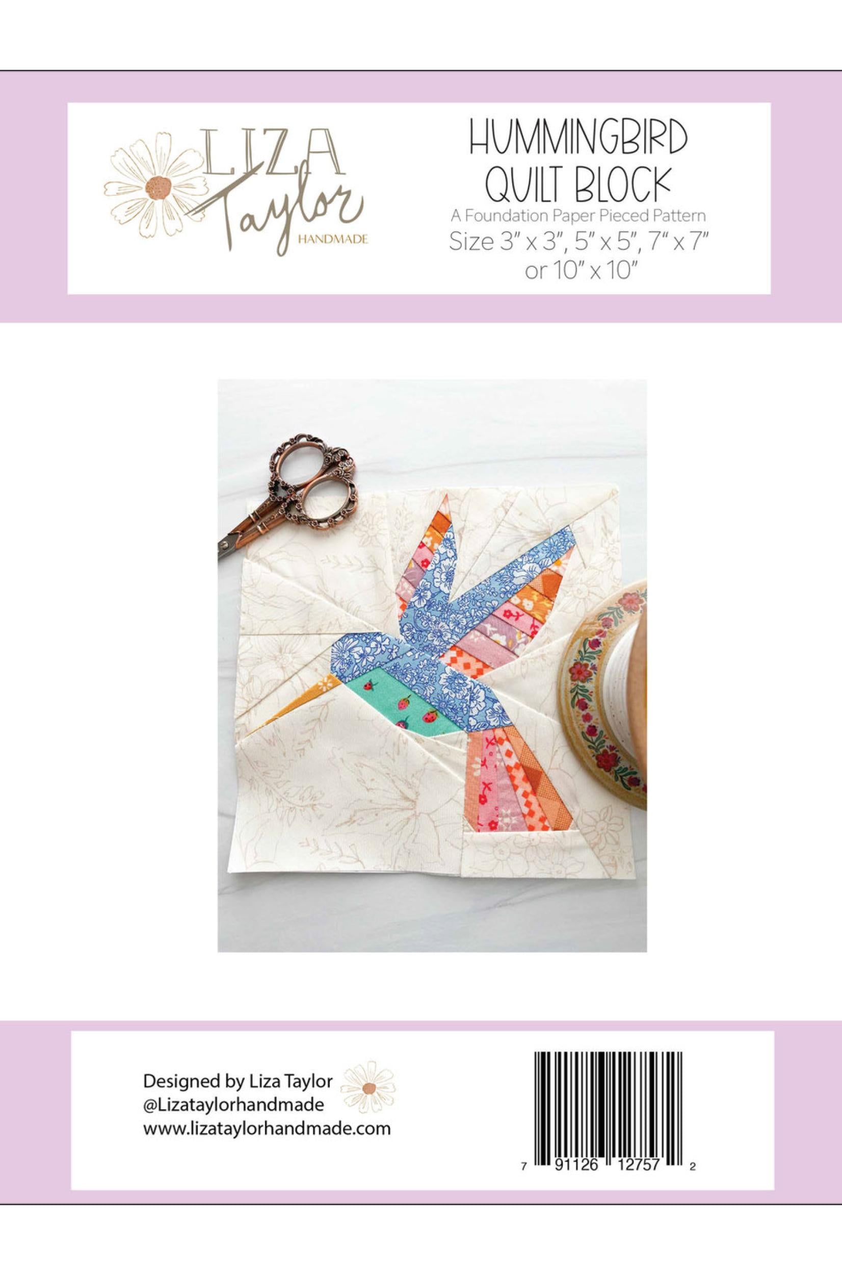 Back cover of a quilting pattern package for the Hummingbird Quilt Block by Liza Taylor, showing a fabric hummingbird patch on a quilted square, with scissors and fabric roll nearby. The package has a white and pale lavender design with product title, sizes, and a barcode.
