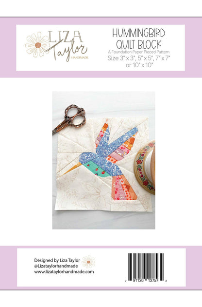 Back cover of a quilting pattern package for the Hummingbird Quilt Block by Liza Taylor, showing a fabric hummingbird patch on a quilted square, with scissors and fabric roll nearby. The package has a white and pale lavender design with product title, sizes, and a barcode.