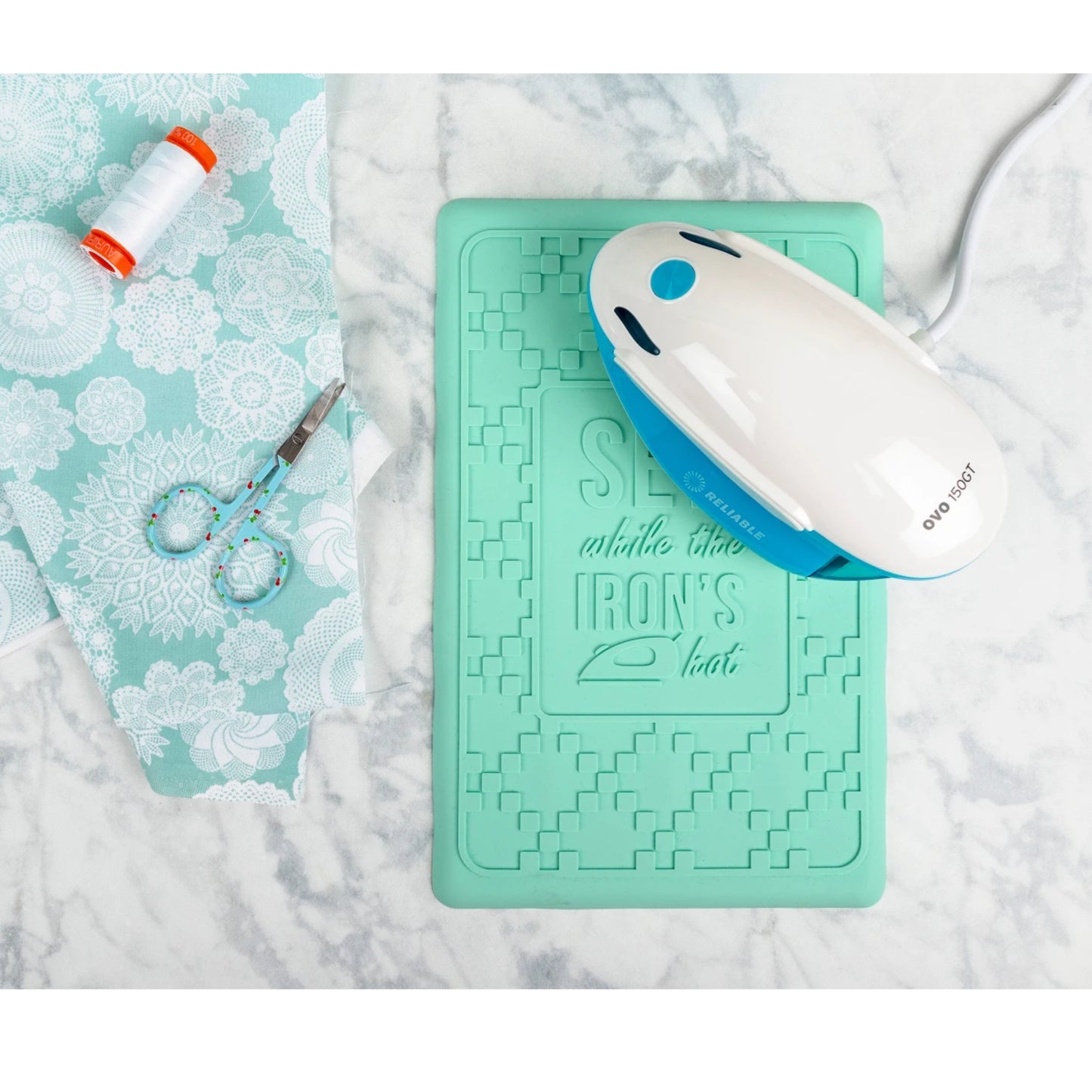 Turquoise ironing mat with a white and blue iron on a marble surface.