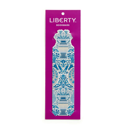 A single decorative bookmark from the brand Liberty, featuring an ornate blue and white scrollwork pattern, presented on its magenta backing card against a plain white background.