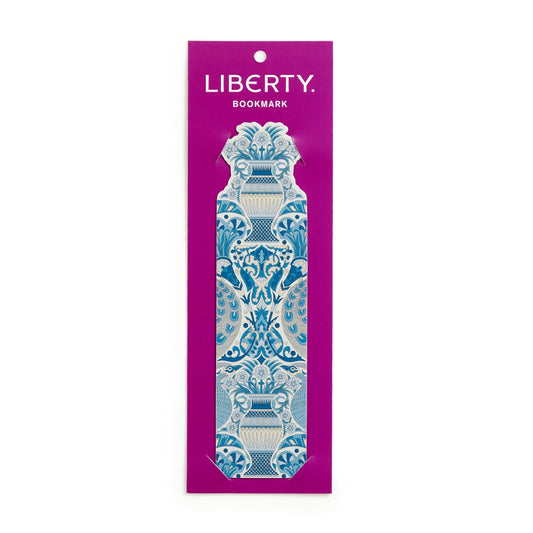 A single decorative bookmark from the brand Liberty, featuring an ornate blue and white scrollwork pattern, presented on its magenta backing card against a plain white background.