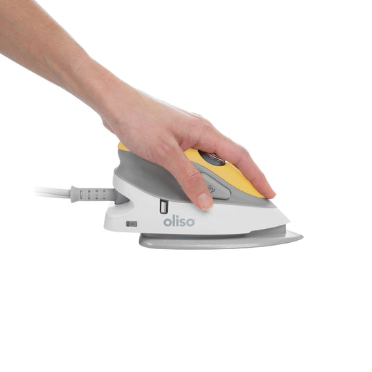 Hand holding a white and yellow oliso iron on a white background