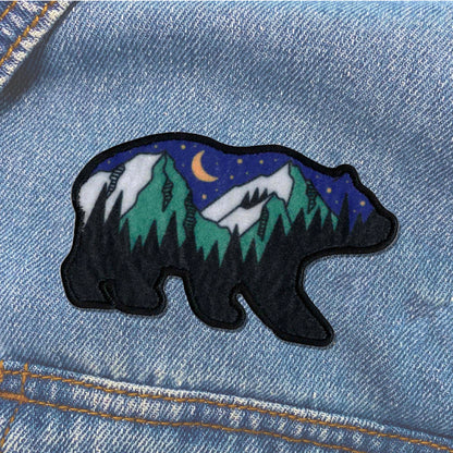 Embroidered bear patch with mountain and moon design on denim fabric