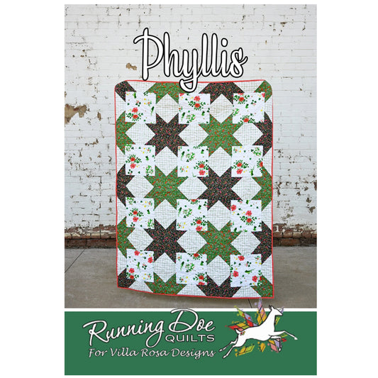 Quilt with star pattern on a white brick wall background, featuring 'Phyllis' and 'Running Doe Quilts' branding.