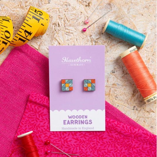 Hawthorn Wooden Earrings packaging with colorful geometric earrings on a textured surface with sewing materials.