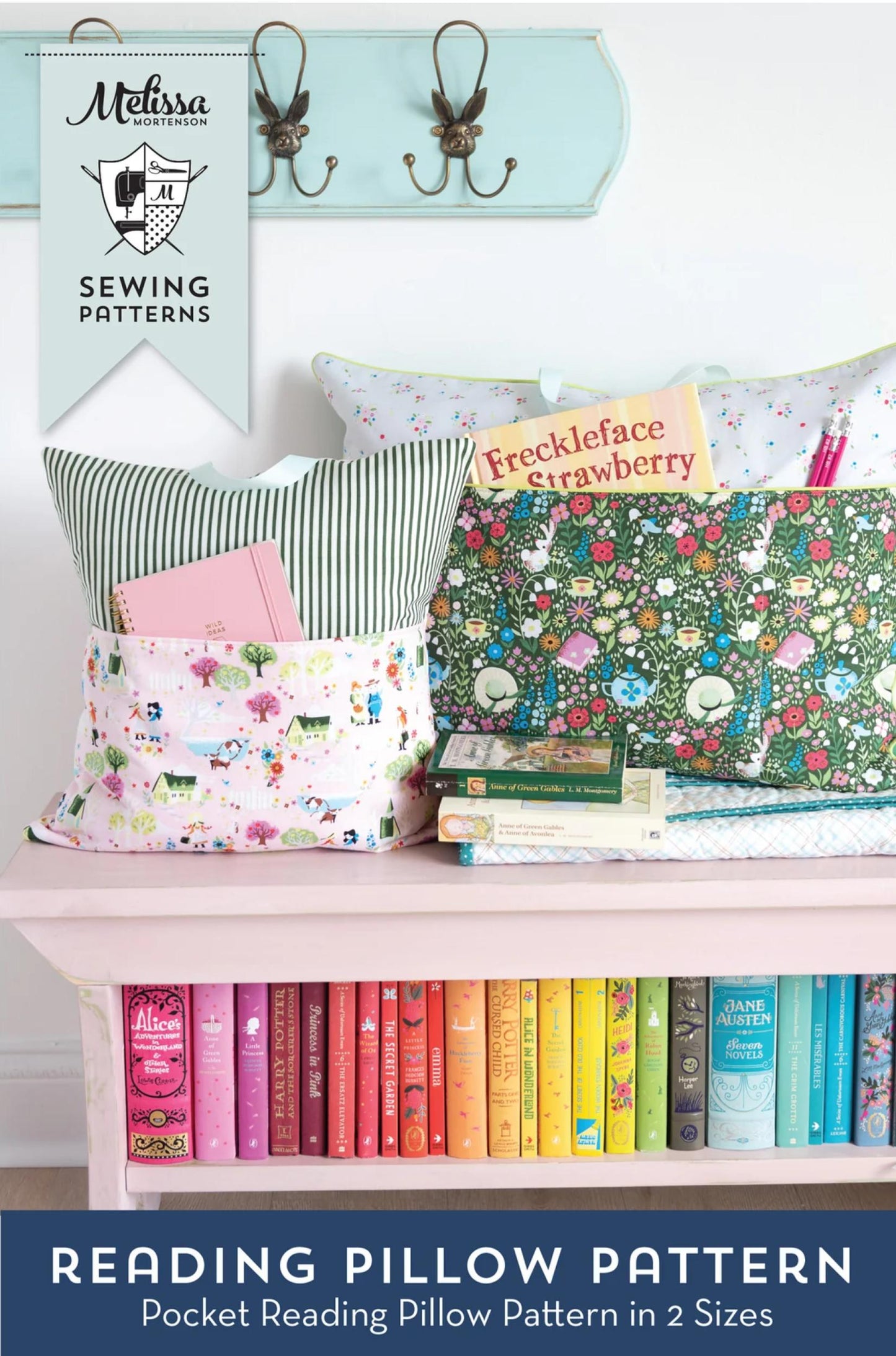 A sewing pattern promotional image for Melissa's Sewing Patterns featuring 'Reading Pillow Pattern' in two sizes. The scene shows several colorful, patterned reading pillows arranged on a pink bench with a row of books underneath, a light blue wall with hooks above, and a banner for Melissa's Sewing Patterns.