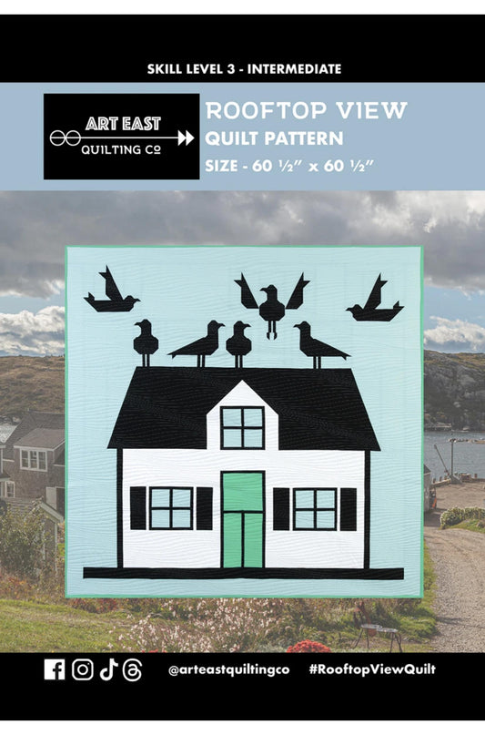 Quilt pattern cover with house and bird design on a rooftop, featuring Art East Quilting Co.