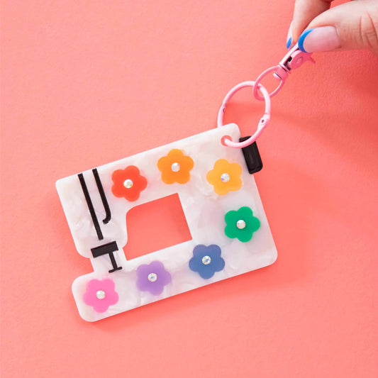 Keychain with sewing machine design and colorful flowers on a pink background