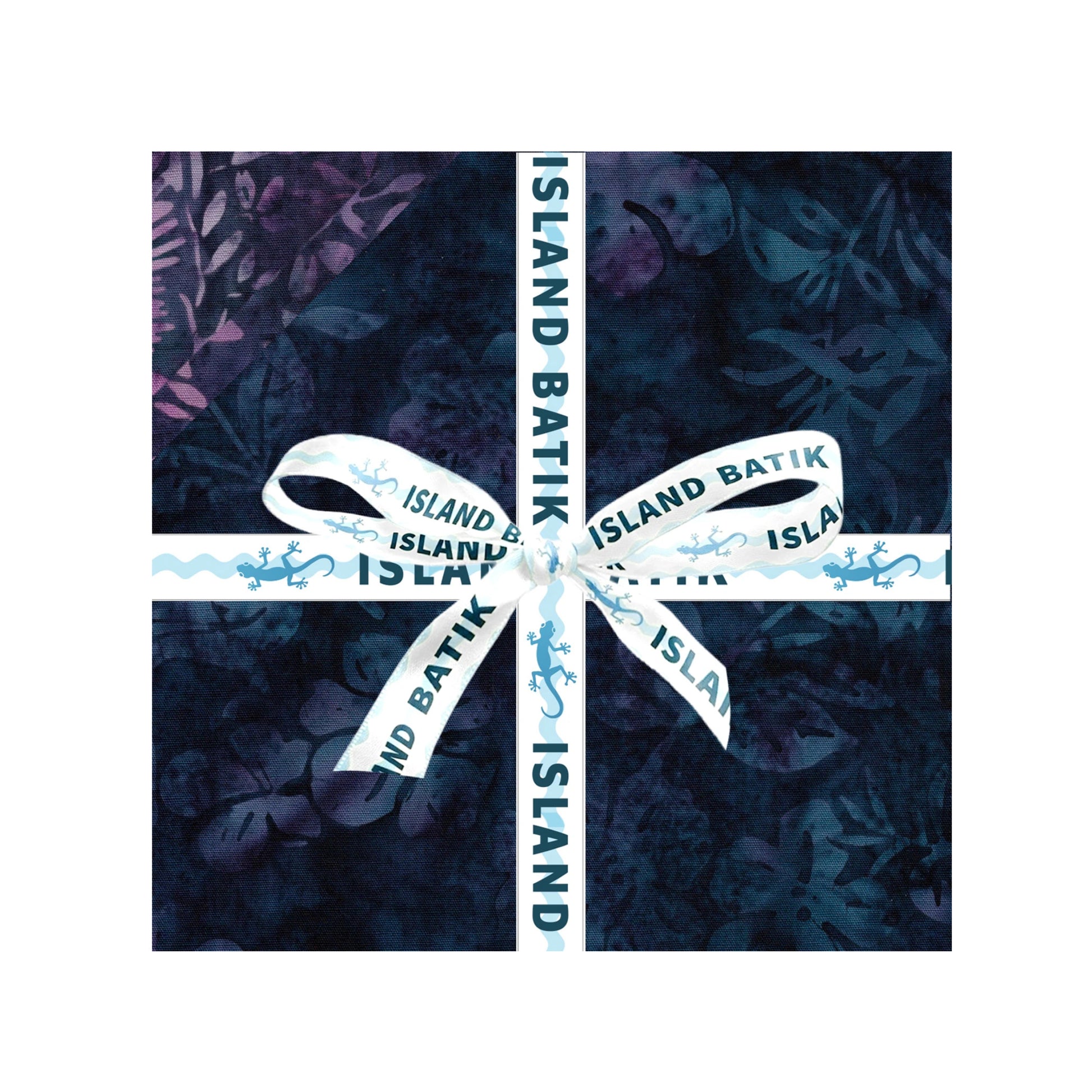 A square fabric bundle wrapped in dark navy batik-patterned paper and tied with a white ribbon printed with 'ISLAND BATIK' and small blue motifs, shown on a white background.