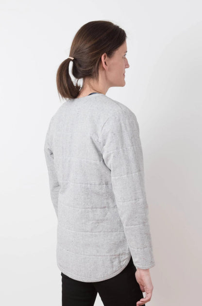 Woman wearing a light gray quilted jacket on a white background