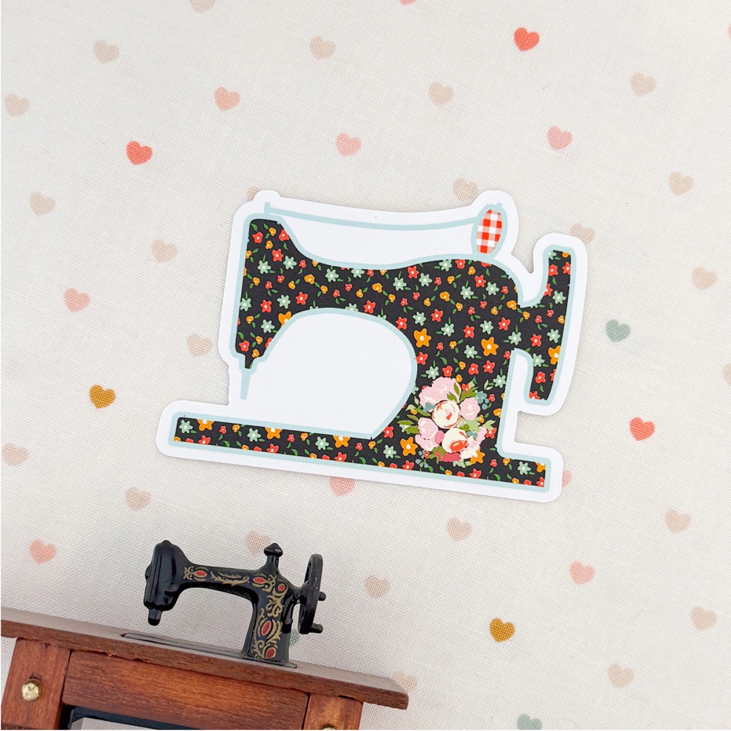 Decorative sewing machine-shaped sign with floral pattern on a wall with heart decorations.