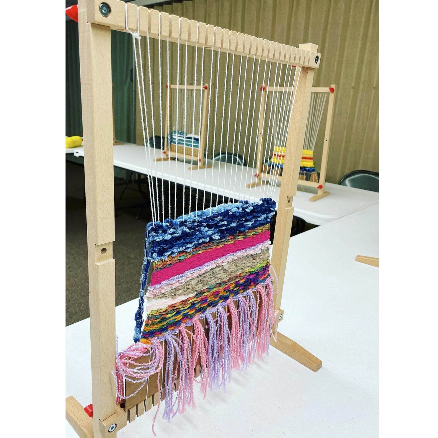 Weaving loom with colorful fabric on a white table