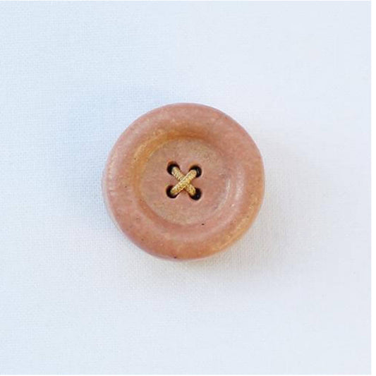 Ponk button with a central gold design on a white background