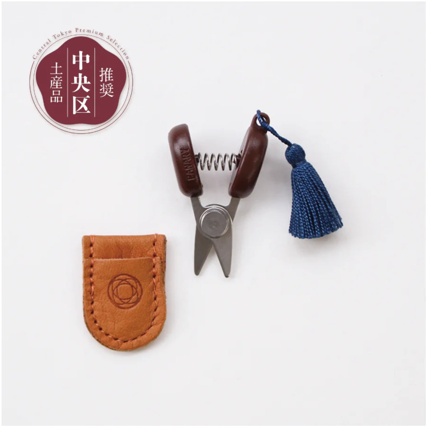 Small scissors with a leather case and tassel on a white background