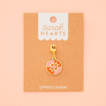 Gold zipper charm on a 'Sarah Hearts' branded card against a beige background