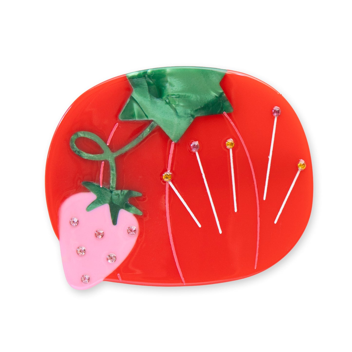 Red tomato-shaped hair clip with green leaves and small decorative items on a white background