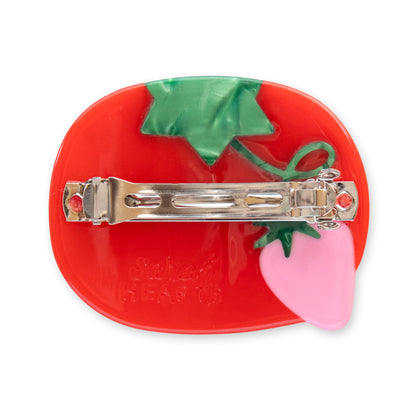 Red tomato-shaped hair clip with a pink base and green leaves on a white background