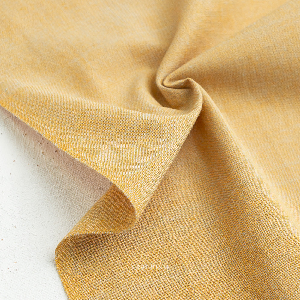 Close-up of yellow fabric with a subtle pattern on a white background