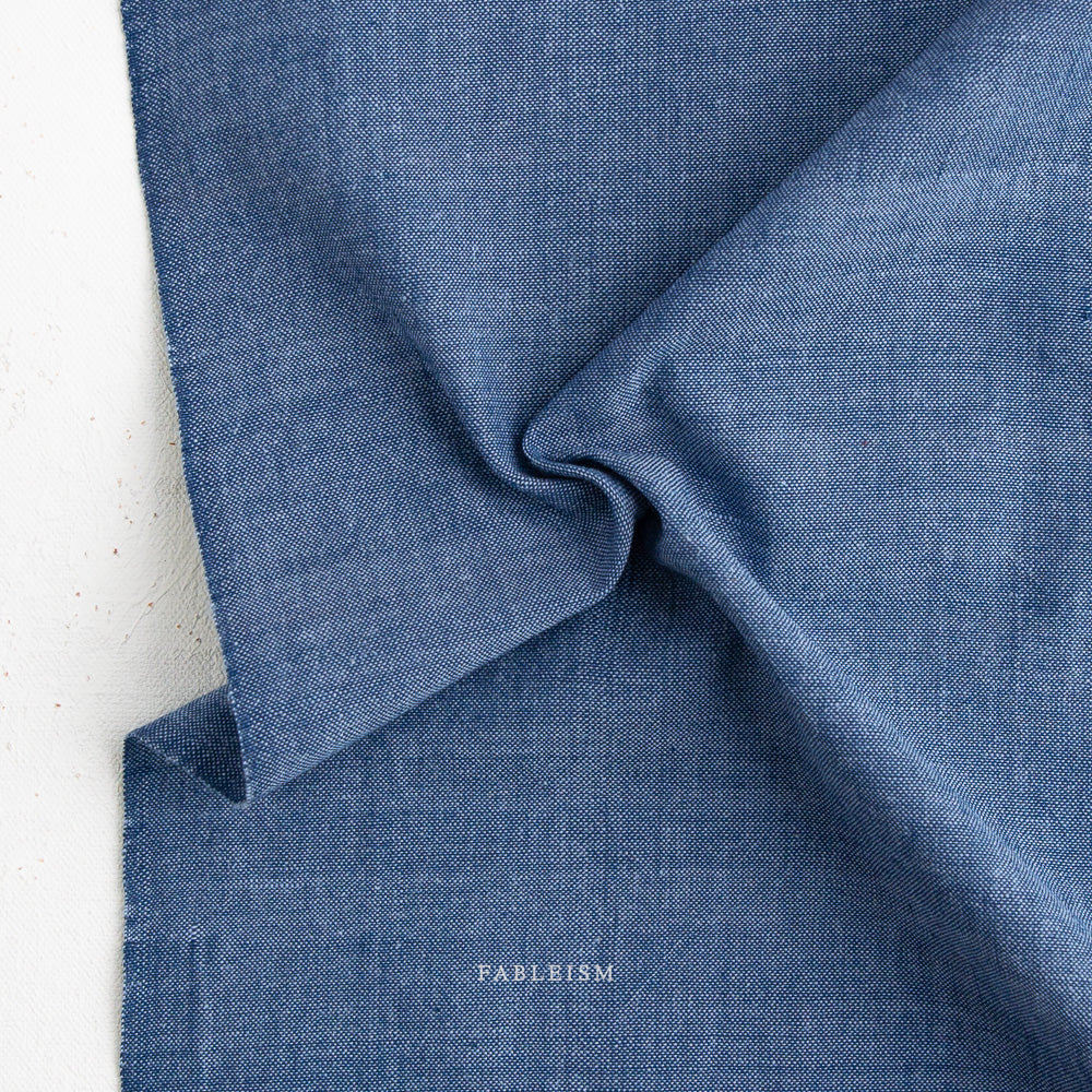 Close-up of blue fabric with 'Fableism' branding on a white background