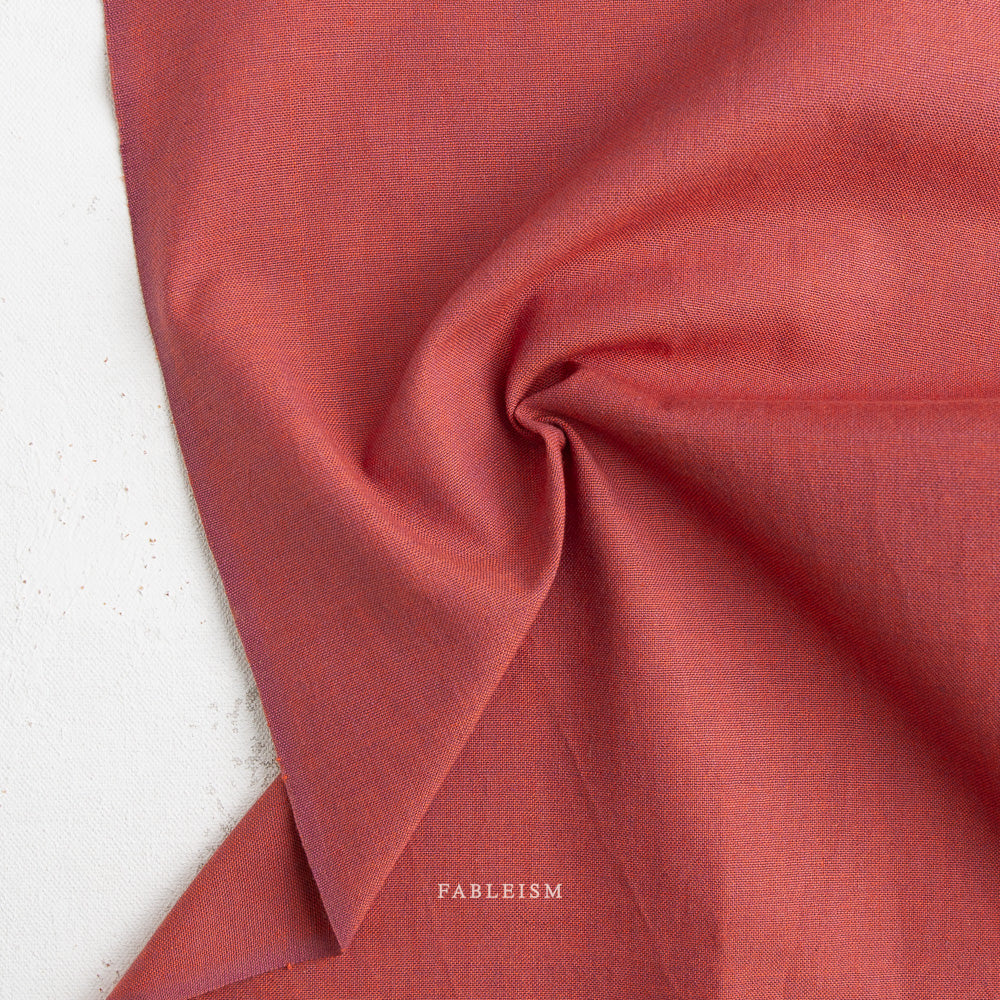 Close-up of red fabric with 'Fableism' branding on a white background