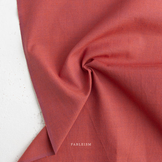 Close-up of red fabric with 'Fableism' branding on a white background