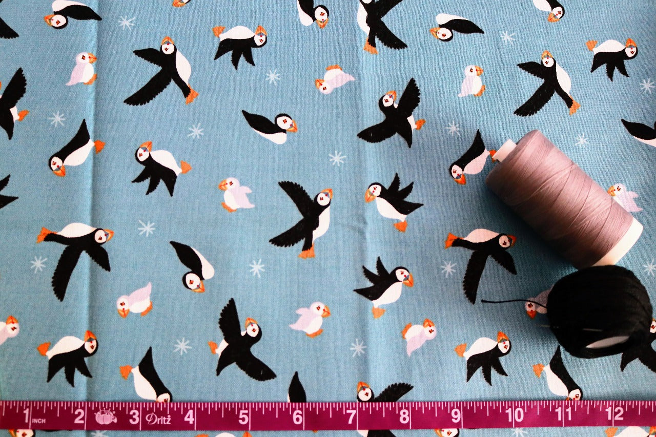 Puffins on Blue fabric with tape measurer and spools of thread to show scale of pattern image